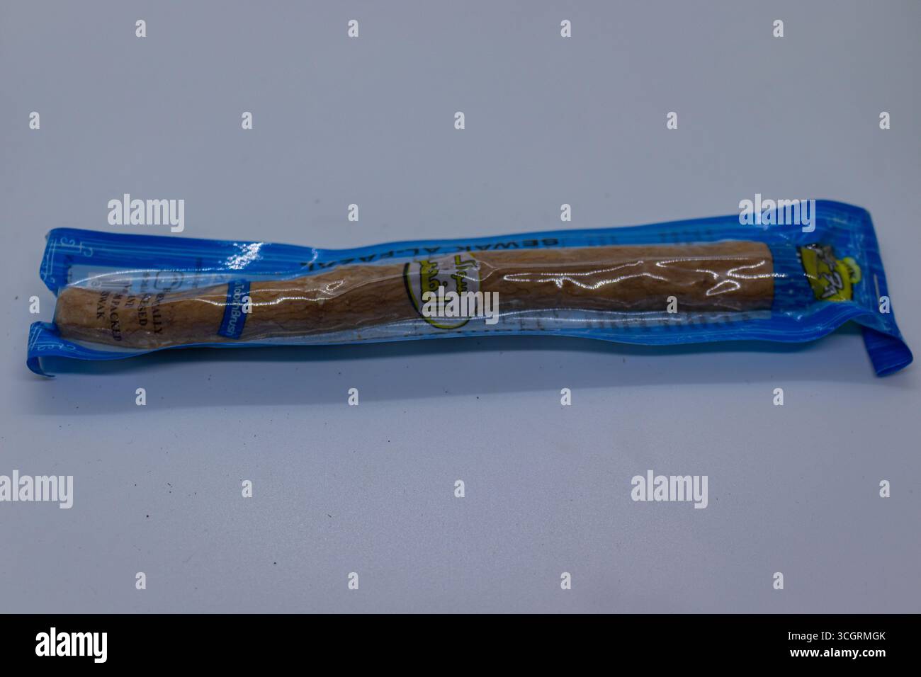 Bâton de brosse à dents Miswak naturel emballé dans un emballage bleu sur fond blanc Banque D'Images
