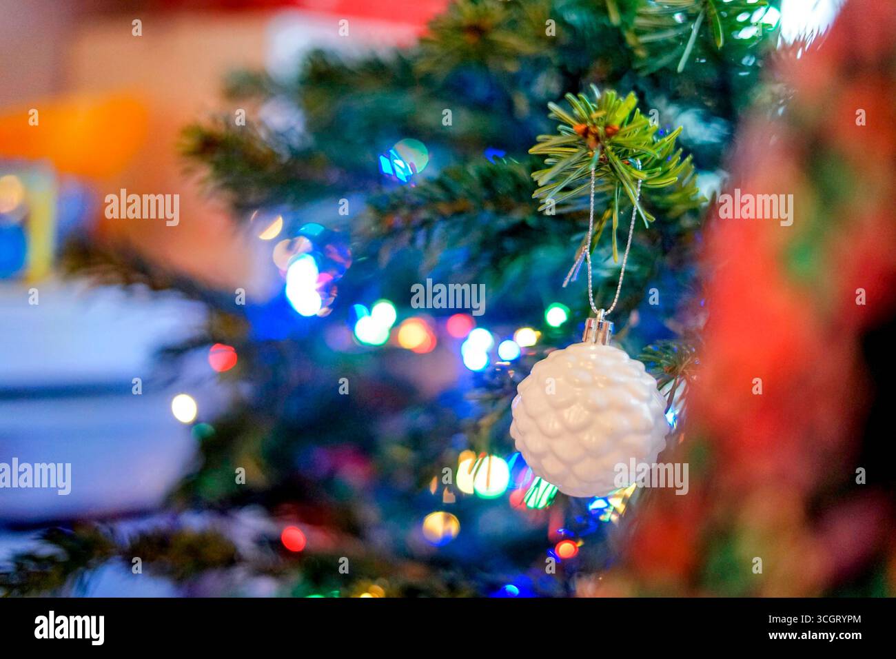 Un sapin de Noël élégant orné de lumières colorées et d'un ornement blanc décoratif, créant une atmosphère de vacances festive. Banque D'Images