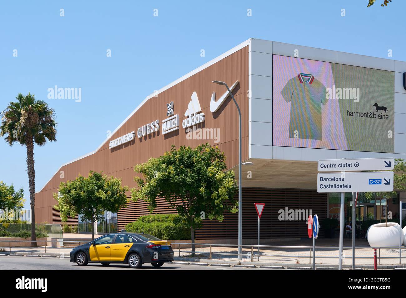 Viladecans. Barcelone - 29 août 2025 : les logos de Nike, Adidas, Guess et Skechers se distinguent sur la façade en bois des Viladecans The style Outlets Banque D'Images