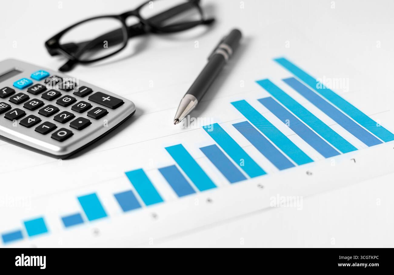 Concept de rapport d'analyse comptable d'entreprise avec une vue rapprochée d'un graphique de croissance réussie, d'une calculatrice, d'un stylo et de lunettes sur un bureau blanc sur backgro Banque D'Images