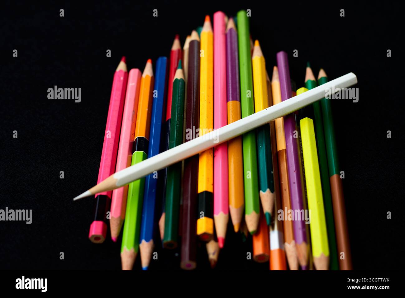 Une variété de crayons de couleur sont empilés de manière artistique, avec des teintes vives sur un fond sombre, mettant en valeur une atmosphère accueillante pour Banque D'Images