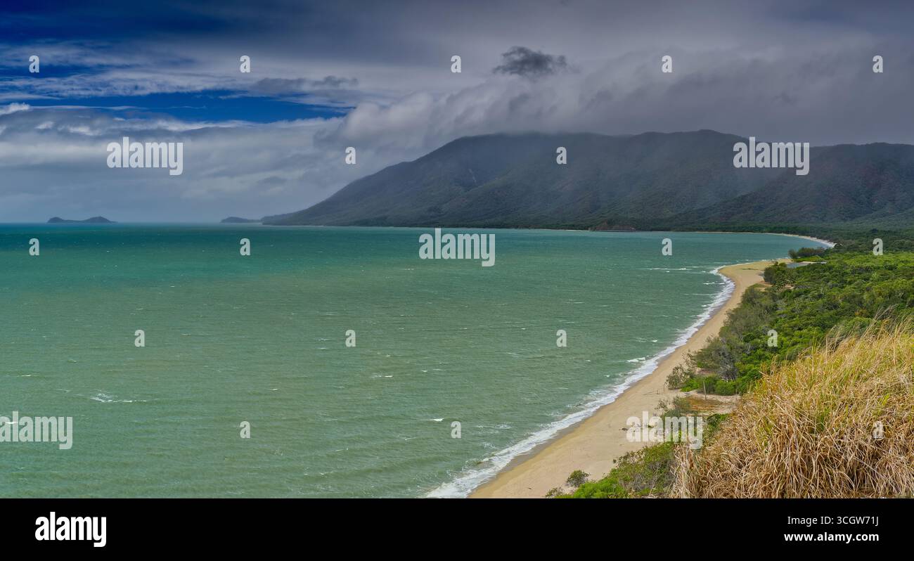 Vue panoramique sur la plage verte de la mer de corail bas nuage gris avec de la pluie à travers des chaînes lointaines avec premier plan au soleil de Yule point, Cairns, Queensland Banque D'Images