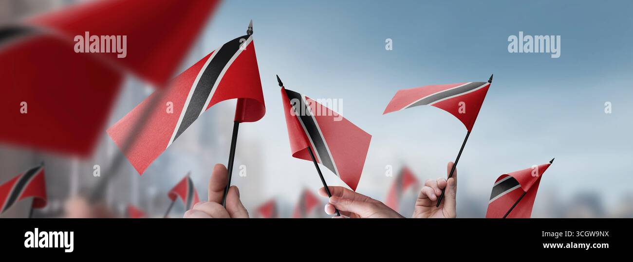Drapeaux de Trinité-et-Tobago dans leurs mains sur un fond urbain flou Banque D'Images