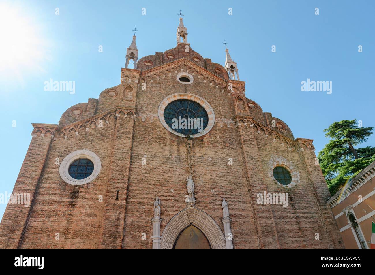 Église vénitienne historique présentant une architecture gothique avec des fenêtres circulaires et des sculptures en pierre sur la façade en briques rouges Banque D'Images