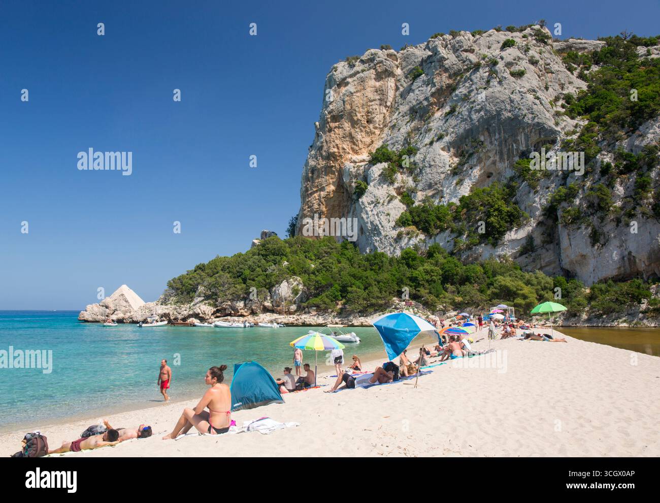 Golfe d'Orosei et parc national de Gennargentu, Dorgali, Nuoro, Sardaigne, Italie. Touristes se relaxant sur la plage de sable sous les falaises abruptes, Cala Luna. Banque D'Images