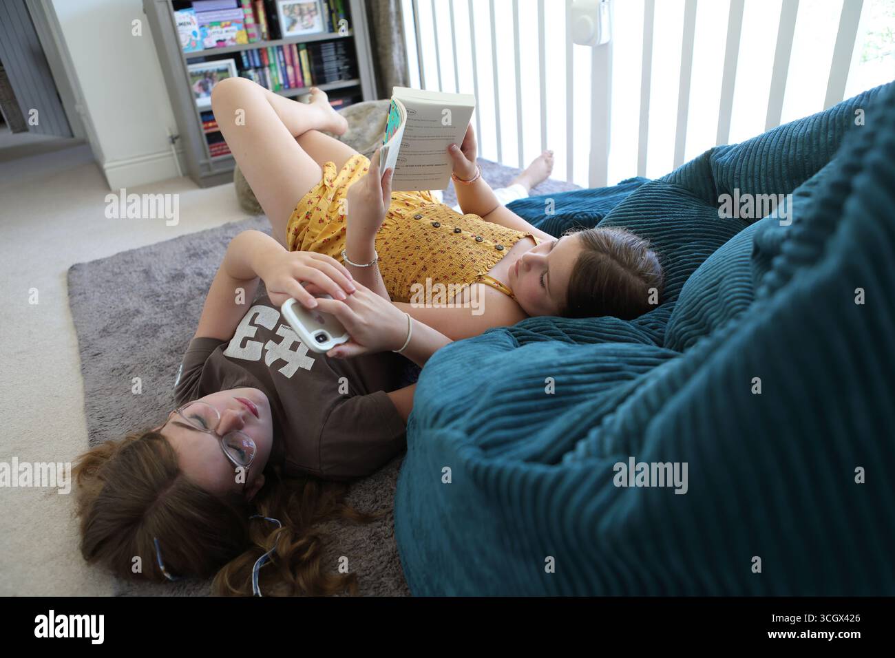 Deux filles on lit le livre autres regards sur le concept de téléphone intelligent lecture de livres d'alphabétisation screentime écran temps adolescent adolescents se détendre Banque D'Images