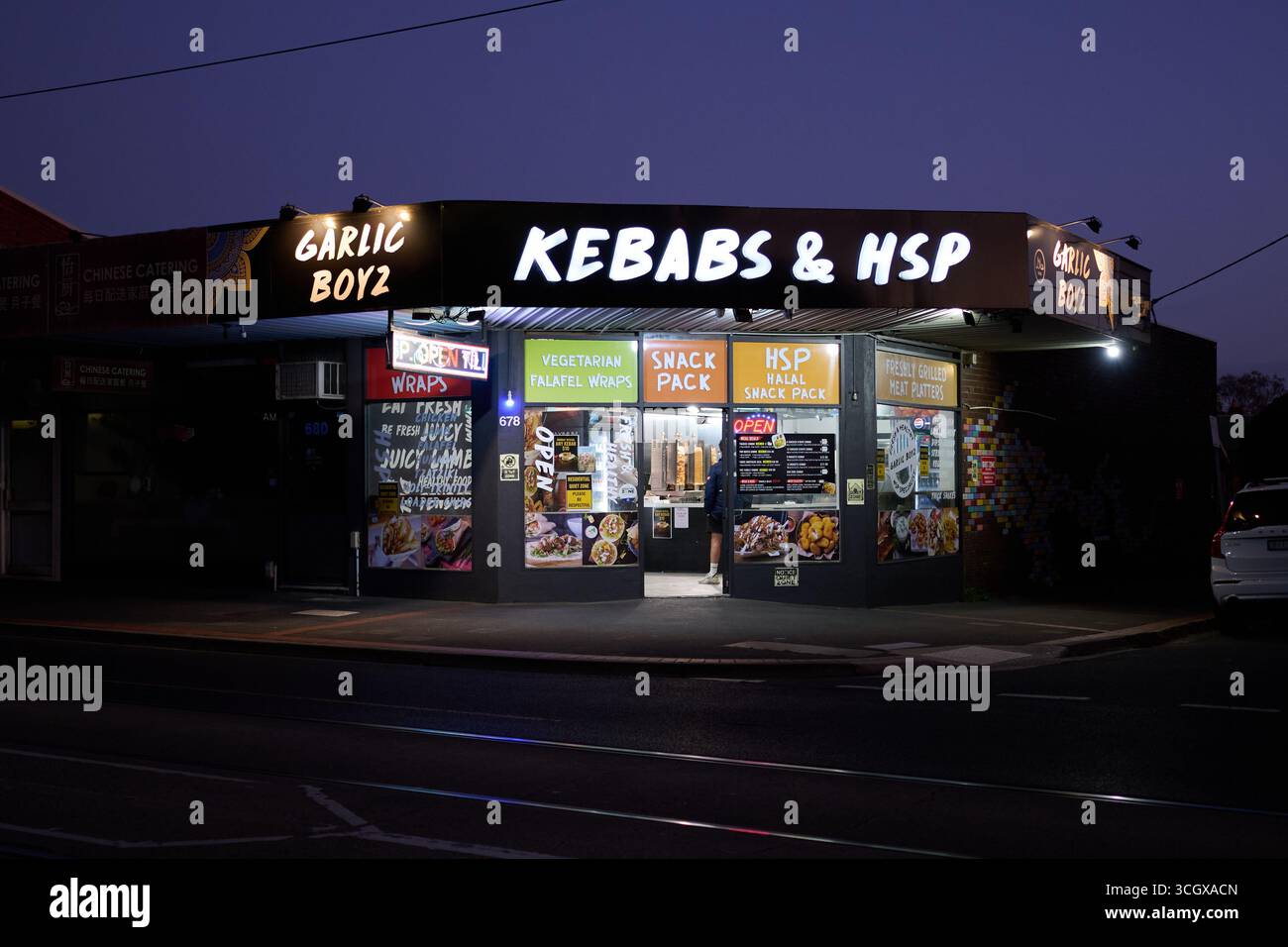 Extérieur illuminé de Garlic Boyz Kebab et magasin HSP, en début de soirée Banque D'Images