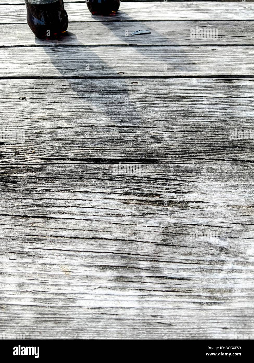 Un gros plan de chaussures laissant des ombres sur une surface en bois altérée, capturant l'essence des aventures en plein air et le charme rustique. Banque D'Images