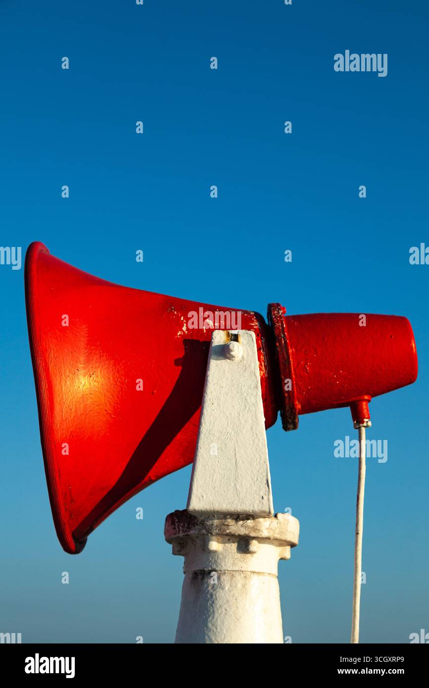 Une corne de navire rouge est fixée sur un support en acier contre un ciel bleu. Banque D'Images