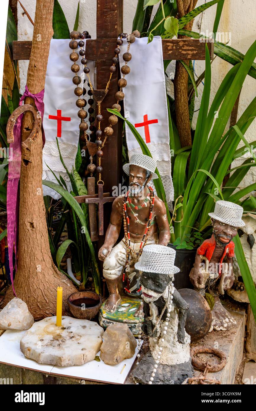 Divinités et objets de l'Umbanda et du Cotolicisme mélangés sur un autel parmi les plantes Banque D'Images