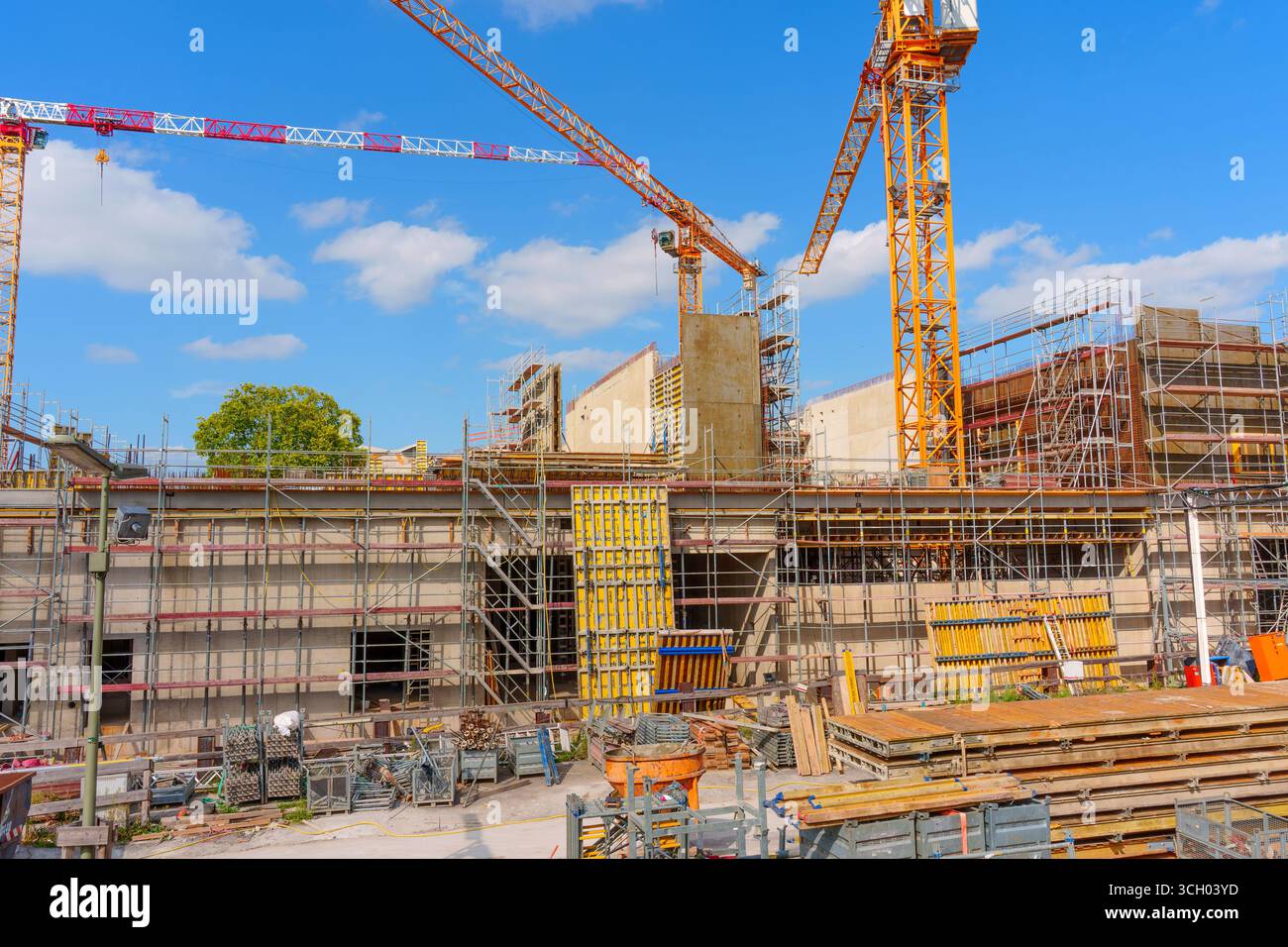 Berlin, Allemagne - 16 août 2025 : chantier de construction actif à Berlin avec grues, échafaudages et matériaux de construction sous un ciel bleu clair. Banque D'Images