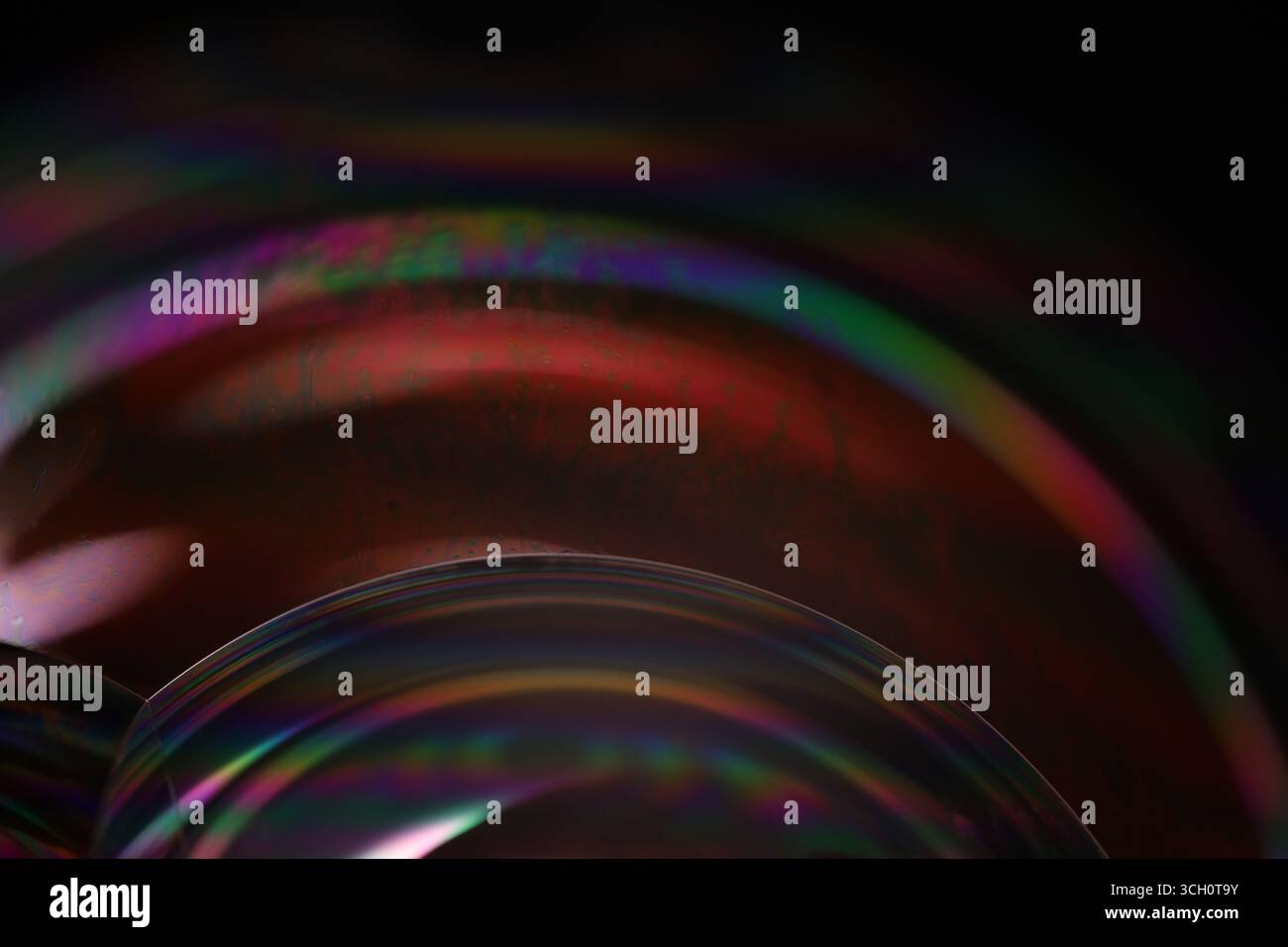 Plan macro d'un bord de bulle de savon avec couleurs arc-en-ciel irisées et mouvement liquide sur fond noir Banque D'Images