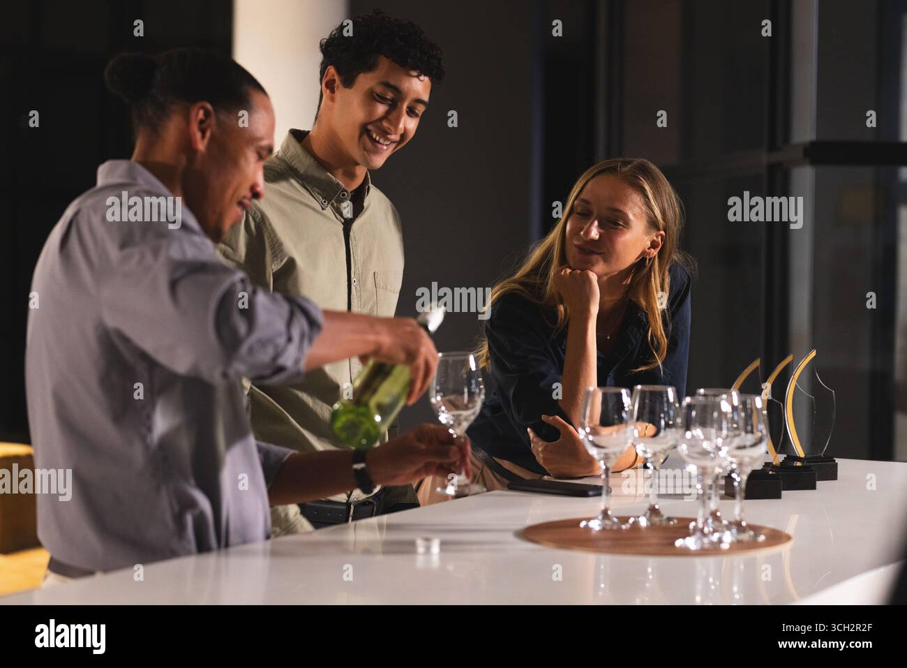 Verser du vin, divers collègues appréciant la conversation au comptoir moderne du bar de bureau Banque D'Images Verser du vin, divers collègues appréciant la conversation au comptoir moderne du bar de bureau Banque D'Images