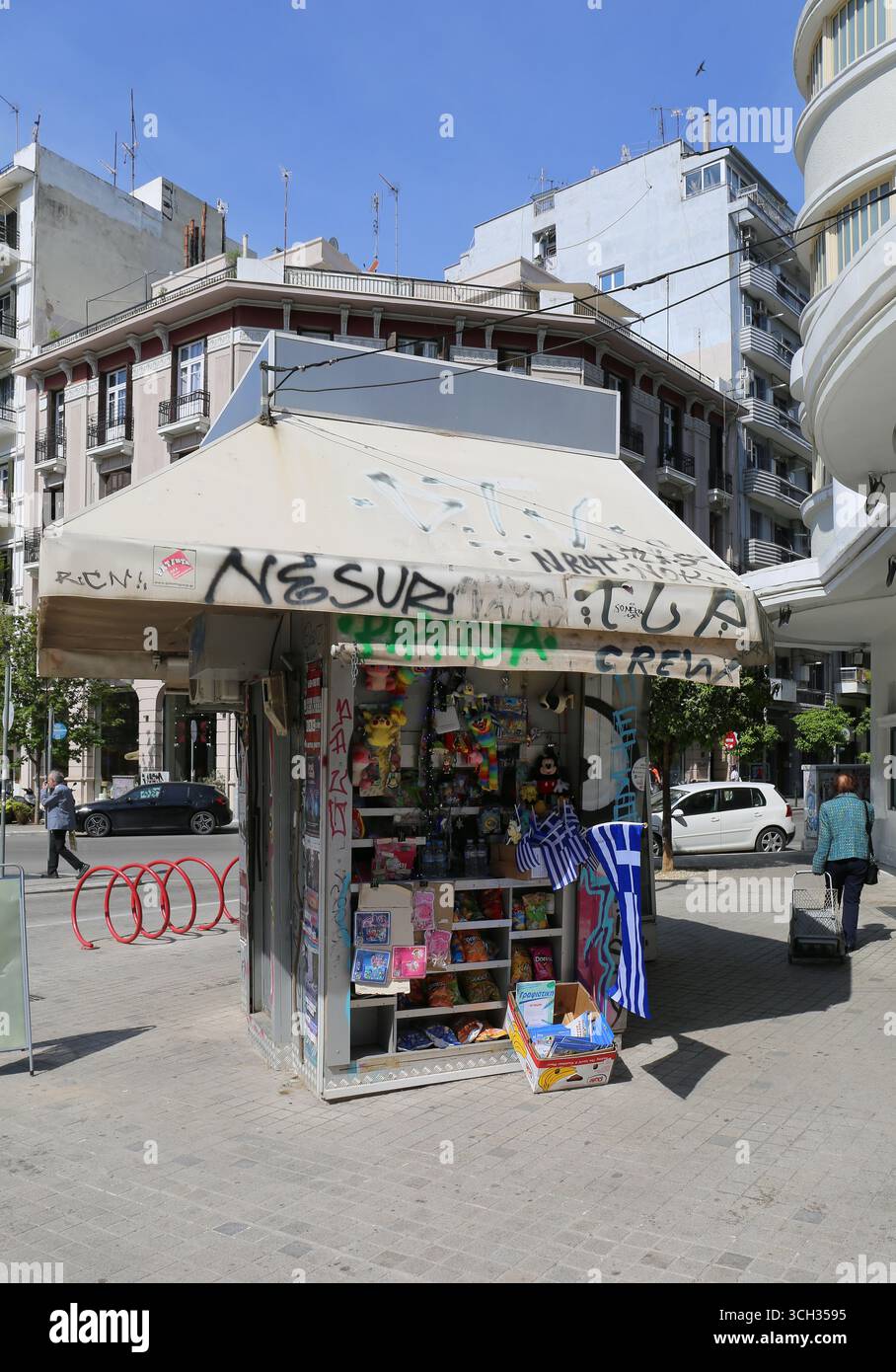 Thessalonique, Grèce-avril 23,2025:personnes non identifiées marchant par le petit kiosque coloré avec drapeaux grecs sur la rue Banque D'Images
