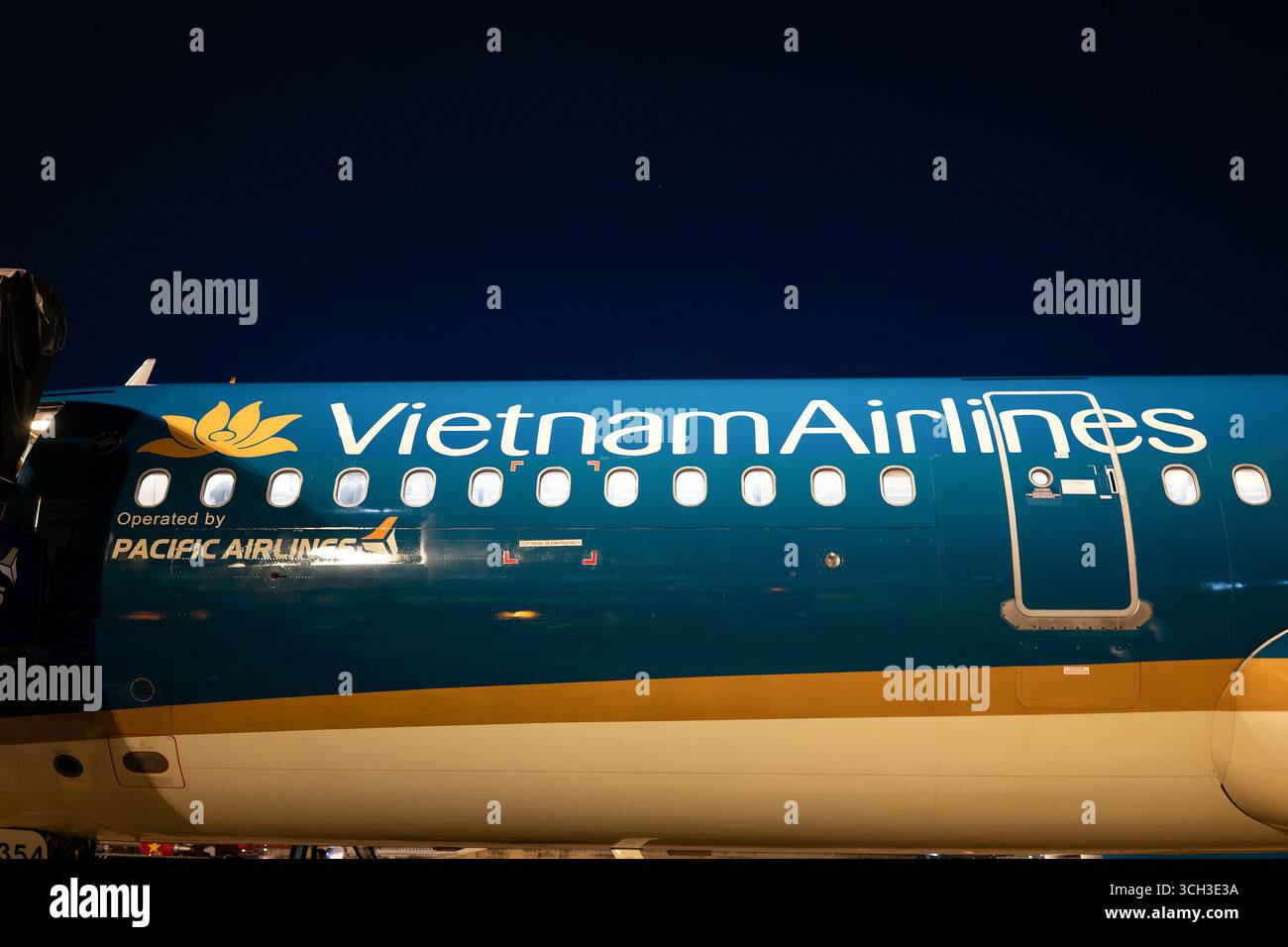Ho Chi Minh-ville, Vietnam - 10 mai 2025 : vue latérale rapprochée du fuselage bleu et or d'un avion Vietnam Airlines avec le logo de la compagnie aérienne an Banque D'Images