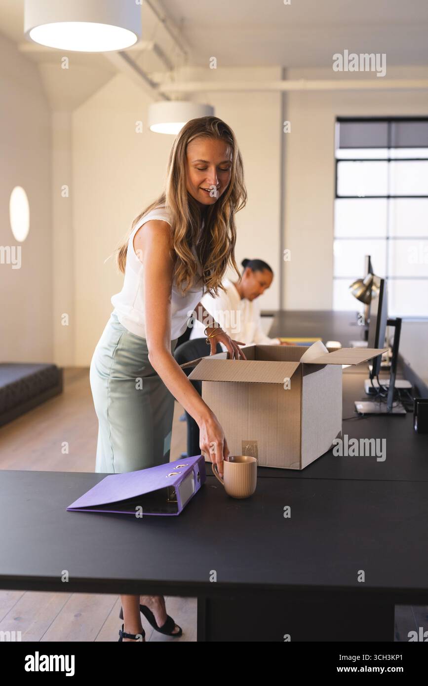 Femme emballant des articles de bureau dans la boîte, se préparant au déménagement au lieu de travail Banque D'Images