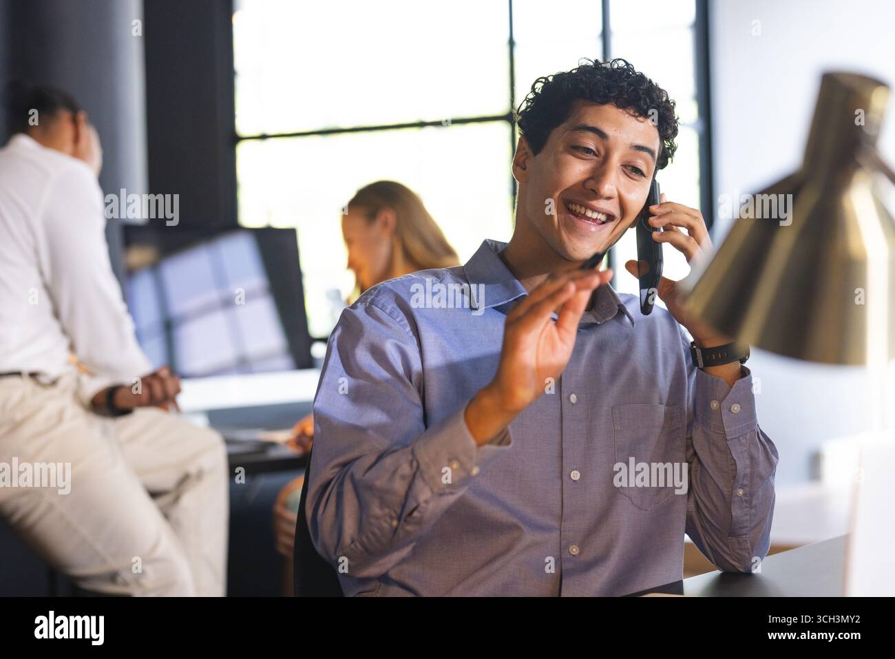 Homme d'affaires souriant sur l'appel téléphonique dans le bureau moderne, gestuel tout en parlant Banque D'Images Homme d'affaires souriant sur l'appel téléphonique dans le bureau moderne, gestuel tout en parlant Banque D'Images