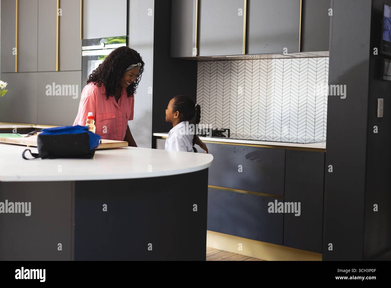 mère et fille parlant dans la cuisine moderne avant l'école, moment de partage, à la maison Banque D'Images mère et fille parlant dans la cuisine moderne avant l'école, moment de partage, à la maison Banque D'Images