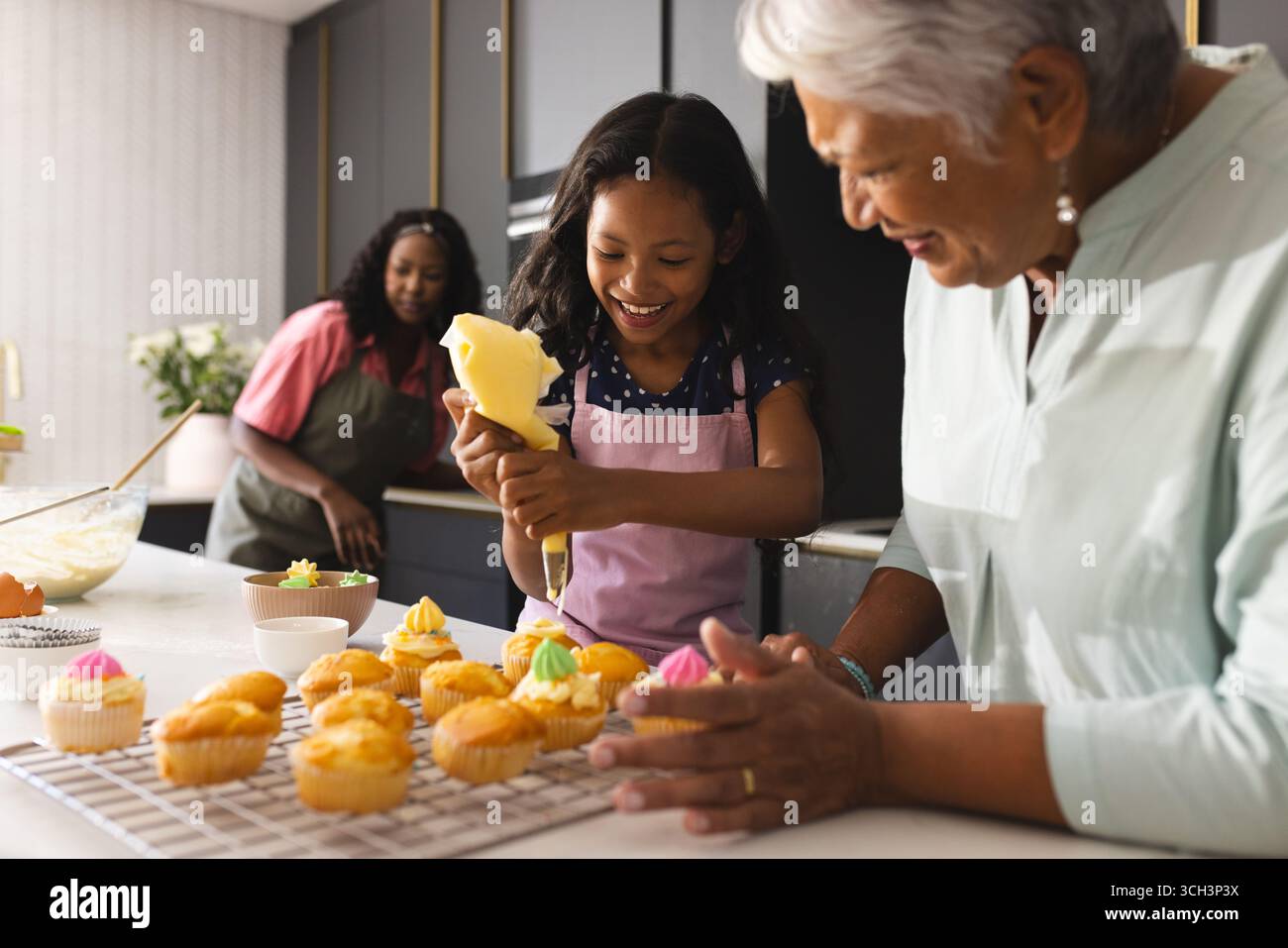 Décorer des cupcakes dans la cuisine, heureux grand-mère et enfant partageant un moment joyeux, à la maison Banque D'Images Décorer des cupcakes dans la cuisine, heureux grand-mère et enfant partageant un moment joyeux, à la maison Banque D'Images