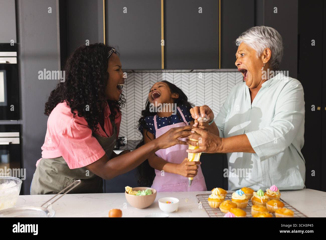 Cuisson de cupcakes , trois générations heureuses riant et liant dans la cuisine, à la maison Banque D'Images Cuisson de cupcakes , trois générations heureuses riant et liant dans la cuisine, à la maison Banque D'Images