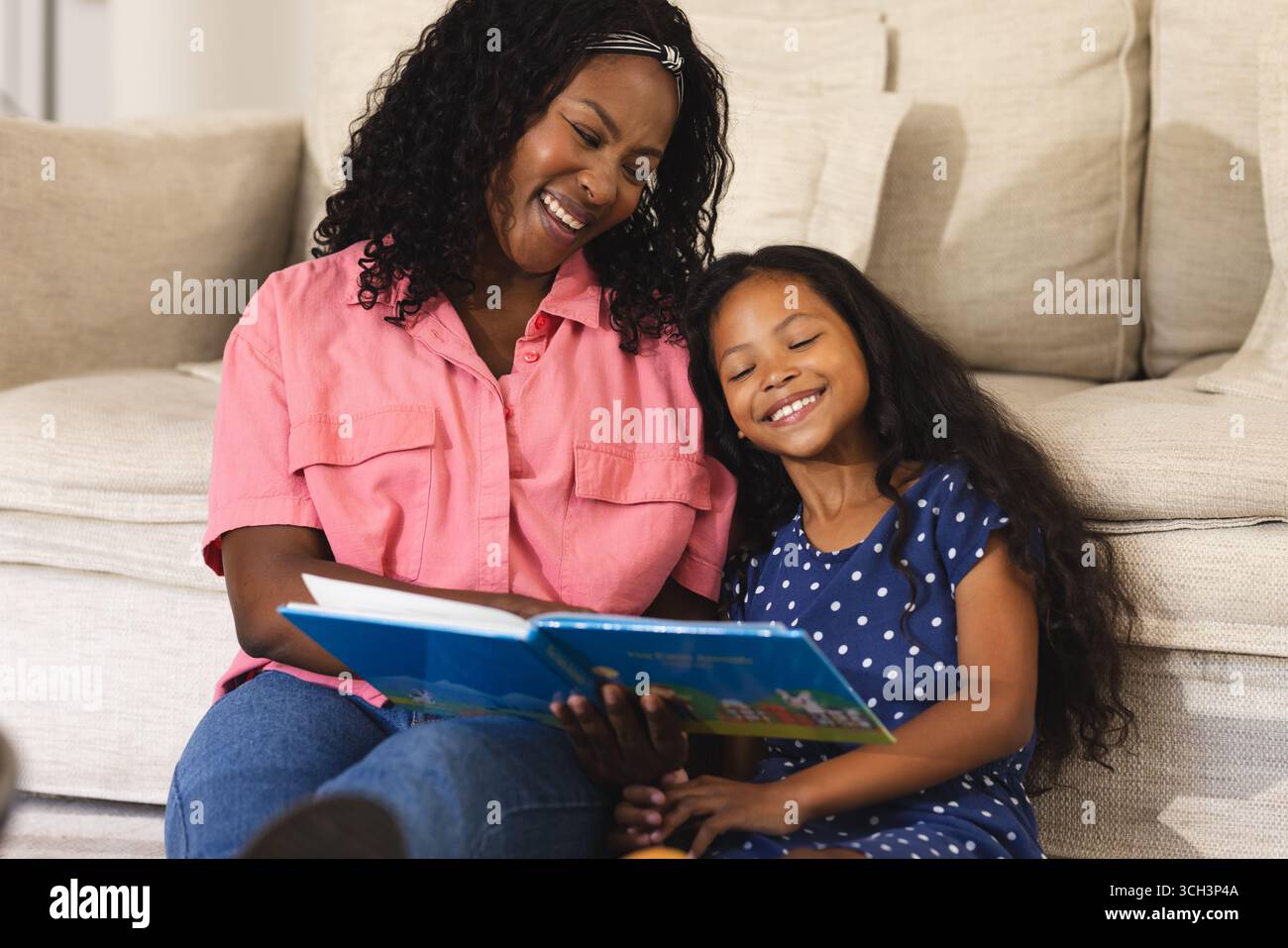 Heureuse mère et fille lisant le livre à la maison, partageant le moment joyeux Banque D'Images Heureuse mère et fille lisant le livre à la maison, partageant le moment joyeux Banque D'Images