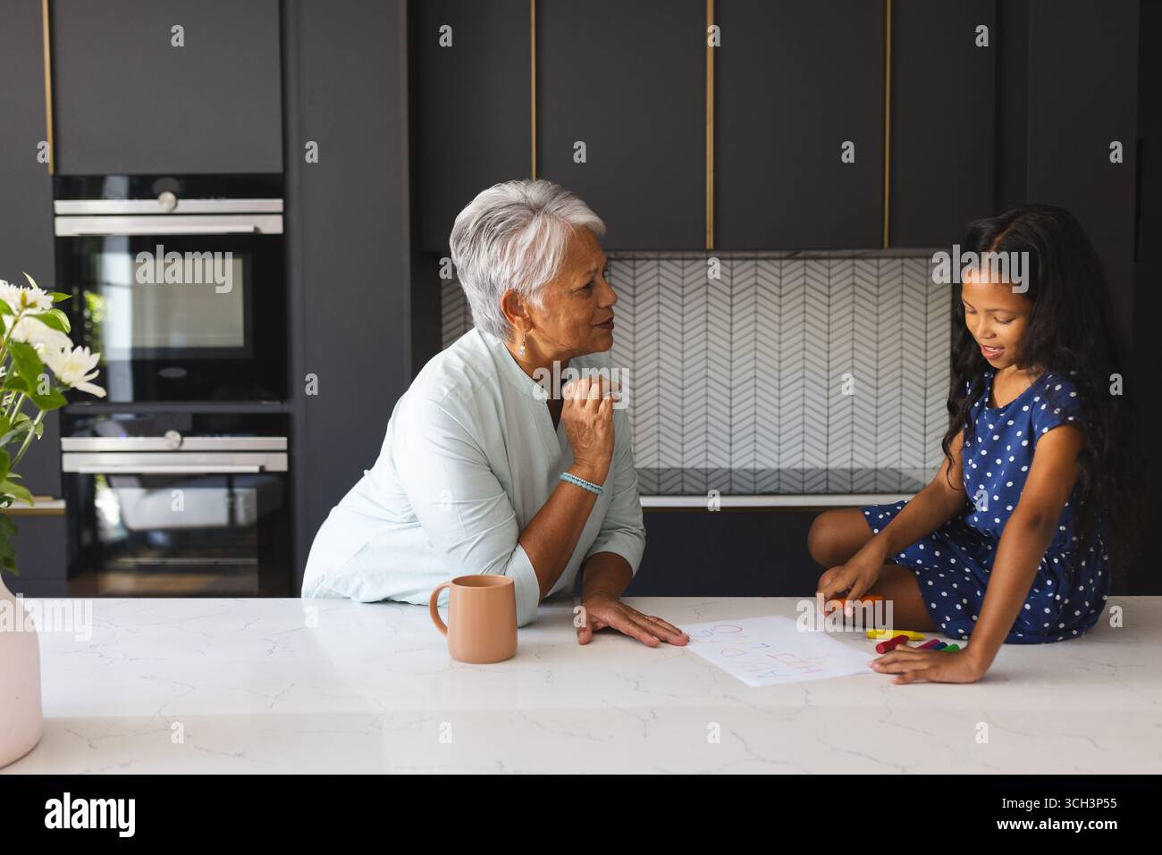 Dessiner ensemble au comptoir de la cuisine, grand-mère et enfant partageant un moment créatif, à la maison Banque D'Images Dessiner ensemble au comptoir de la cuisine, grand-mère et enfant partageant un moment créatif, à la maison Banque D'Images