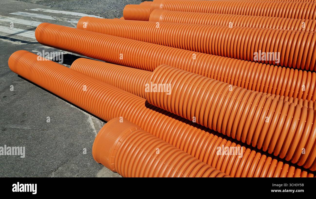Tuyau d'égout ondulé, double couche. Tuyaux empilés, travaux de réparation dans la ville. Tuyaux d'égout orange, gros plan Banque D'Images