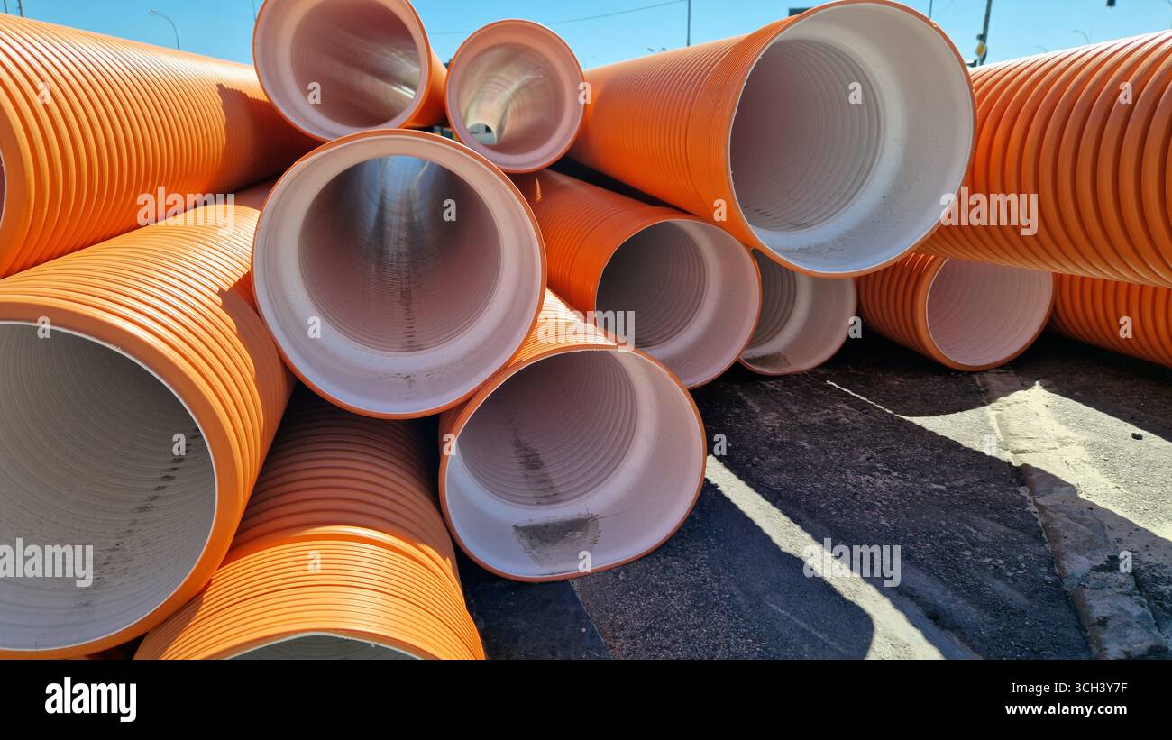 Tuyau d'égout ondulé, double couche. Tuyaux empilés, travaux de réparation dans la ville. Tuyaux d'égout orange, gros plan Banque D'Images