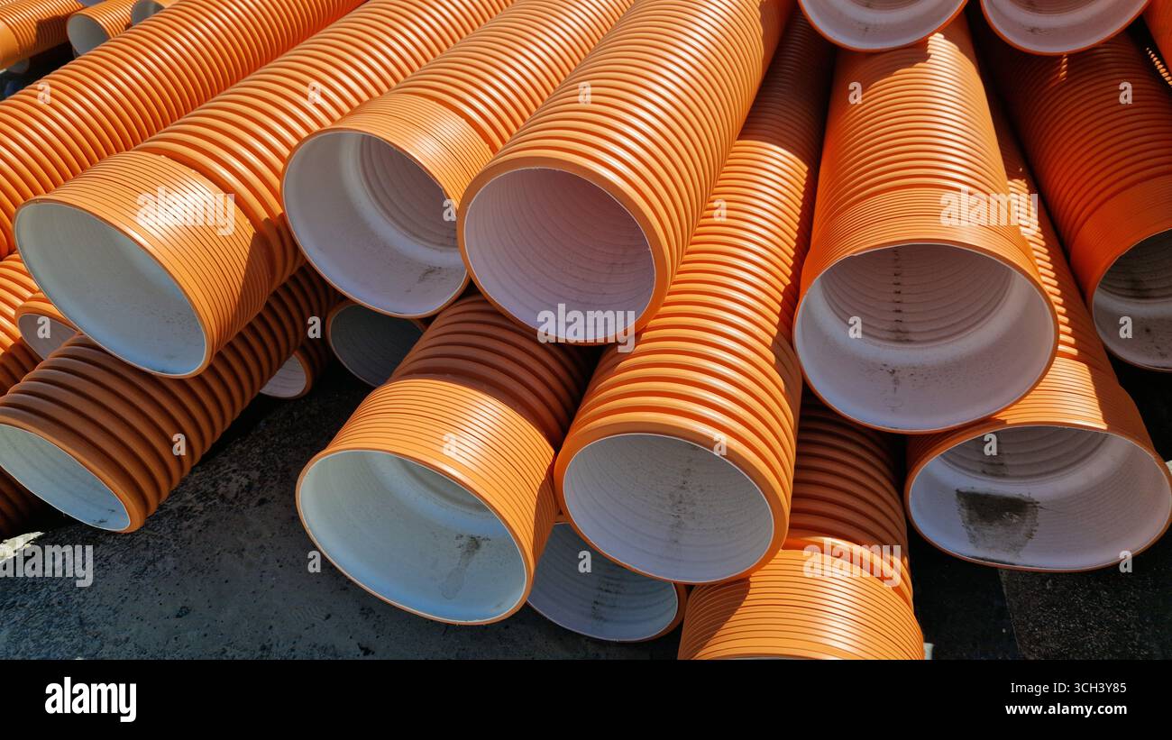 Tuyau d'égout ondulé, double couche. Tuyaux empilés, travaux de réparation dans la ville. Tuyaux d'égout orange, gros plan Banque D'Images