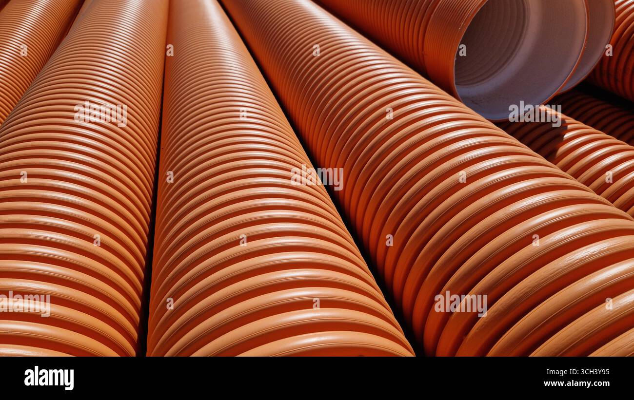 Tuyau d'égout ondulé, double couche. Tuyaux empilés, travaux de réparation dans la ville. Tuyaux d'égout orange, gros plan Banque D'Images
