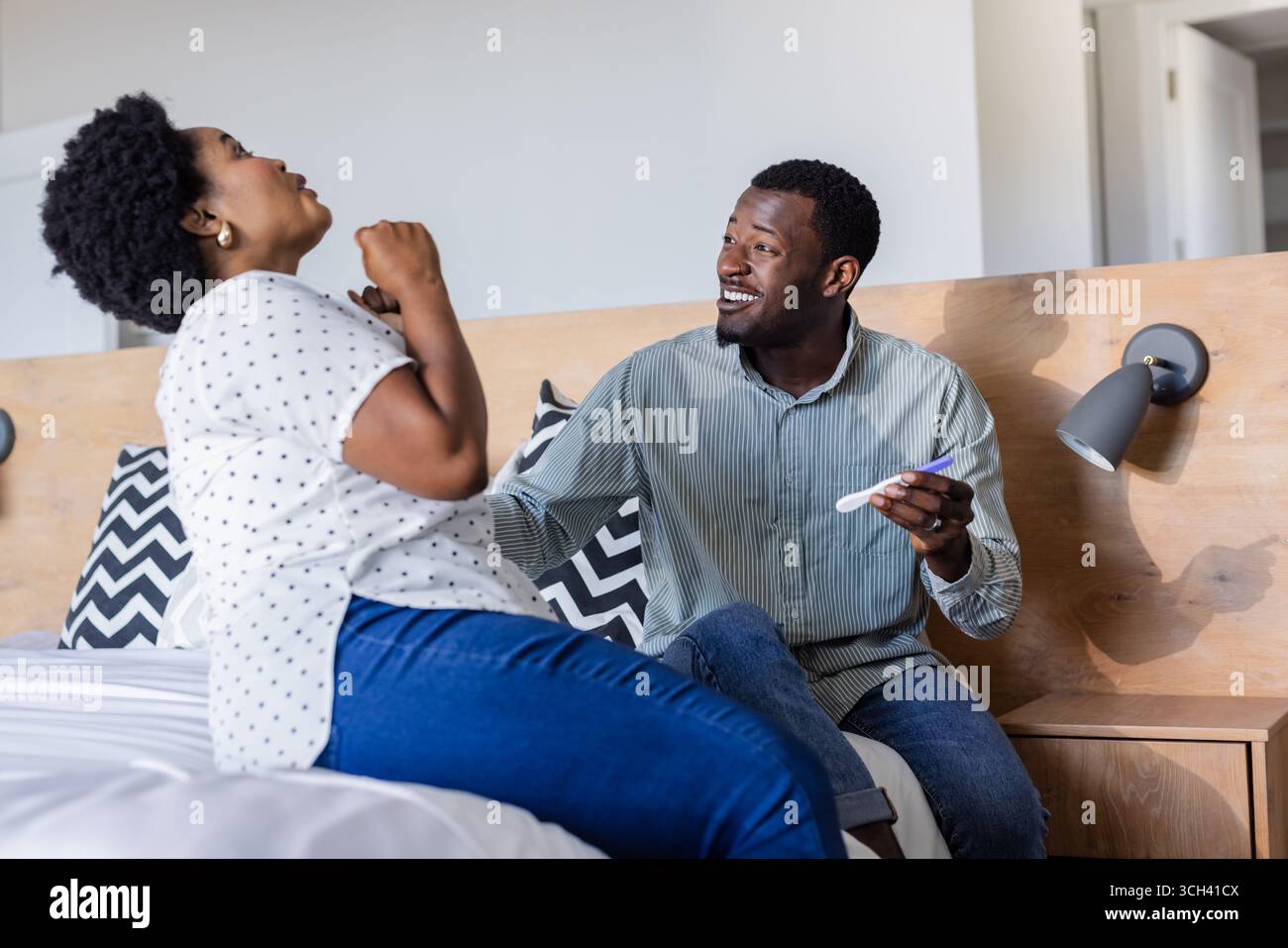 Célébrant le résultat positif du test de grossesse, couple exprimant la joie et l'excitation sur le lit Banque D'Images