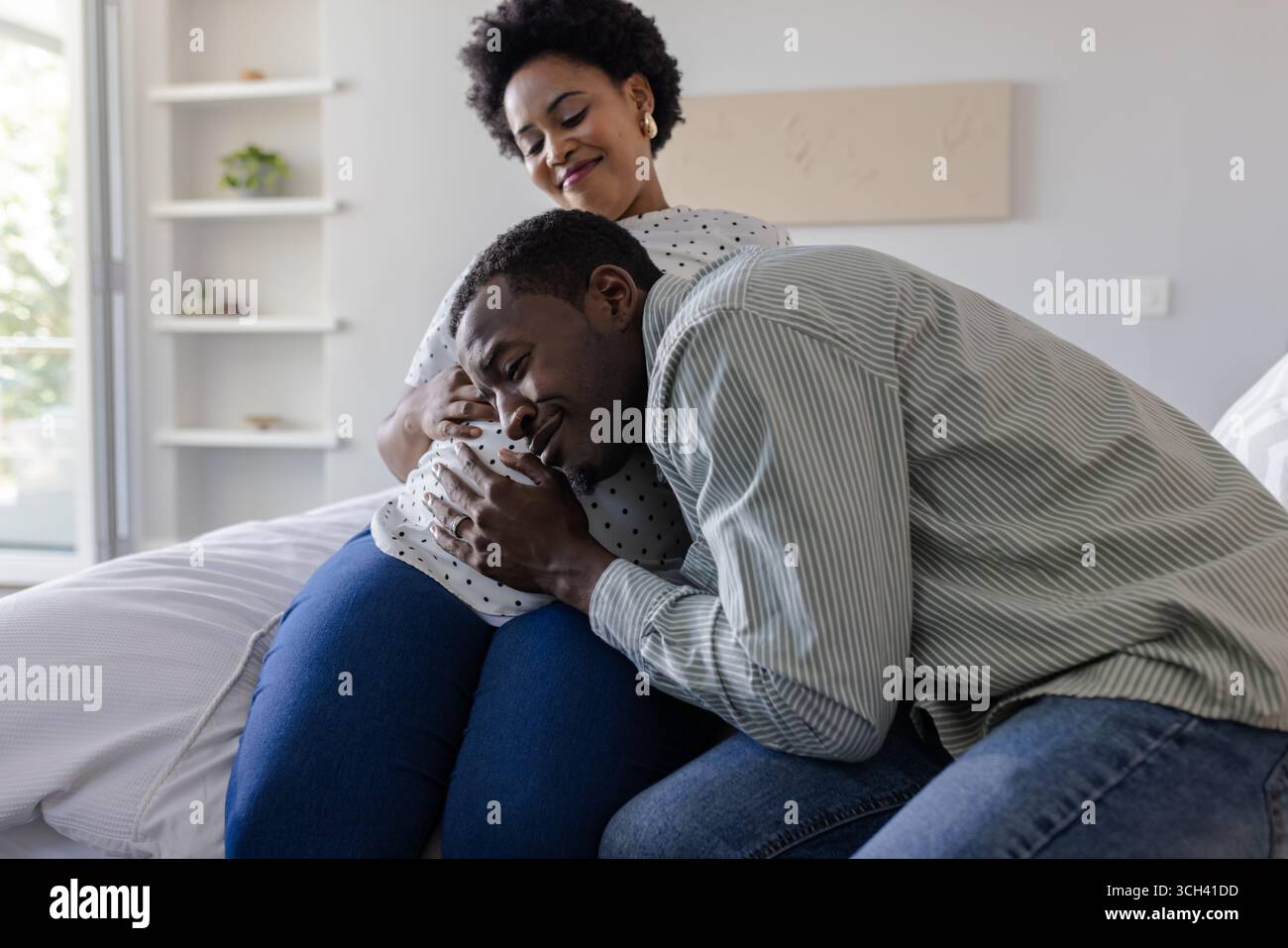 Couple attendu partageant un moment tendre à la maison, mari écoutant le ventre de sa femme Banque D'Images