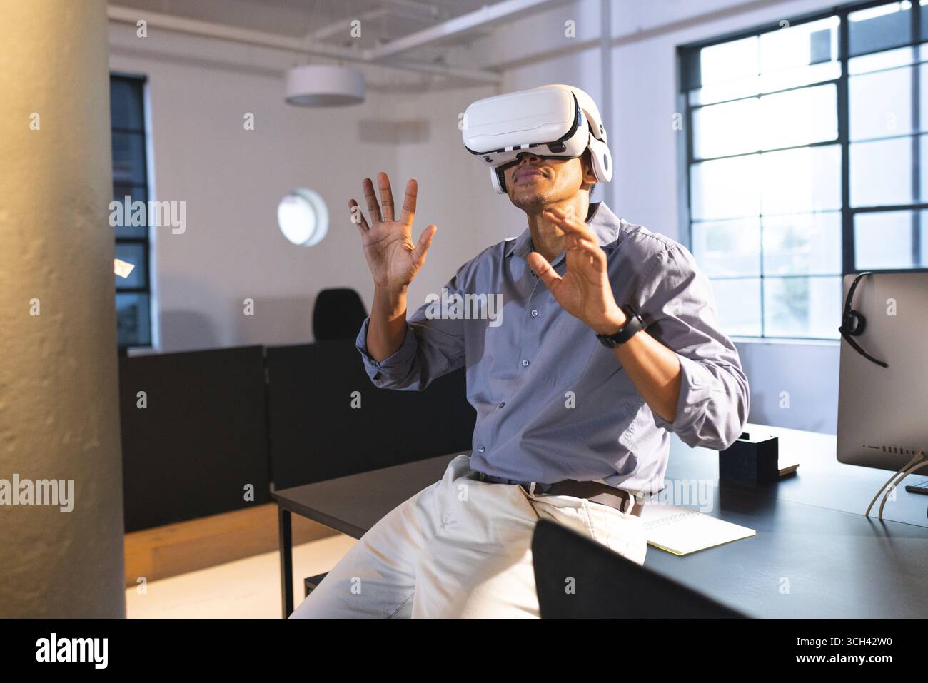 Homme d'affaires utilisant le casque VR au bureau, explorant la réalité virtuelle avec excitation Banque D'Images Homme d'affaires utilisant le casque VR au bureau, explorant la réalité virtuelle avec excitation Banque D'Images