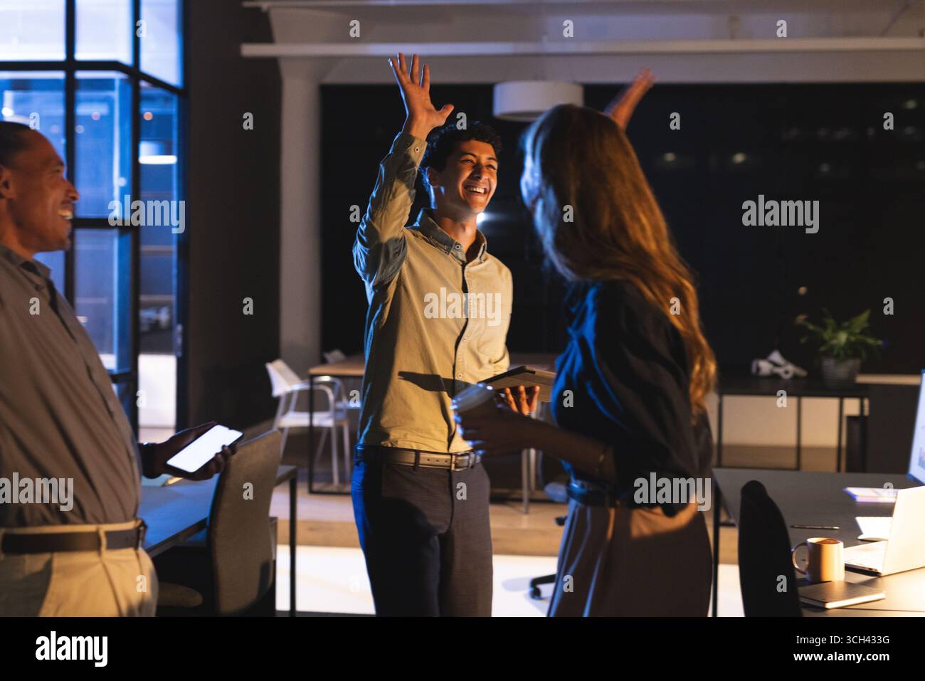 Célébrant le succès, équipe d'affaires haut-fiving dans le bureau moderne la nuit Banque D'Images Célébrant le succès, équipe d'affaires haut-fiving dans le bureau moderne la nuit Banque D'Images