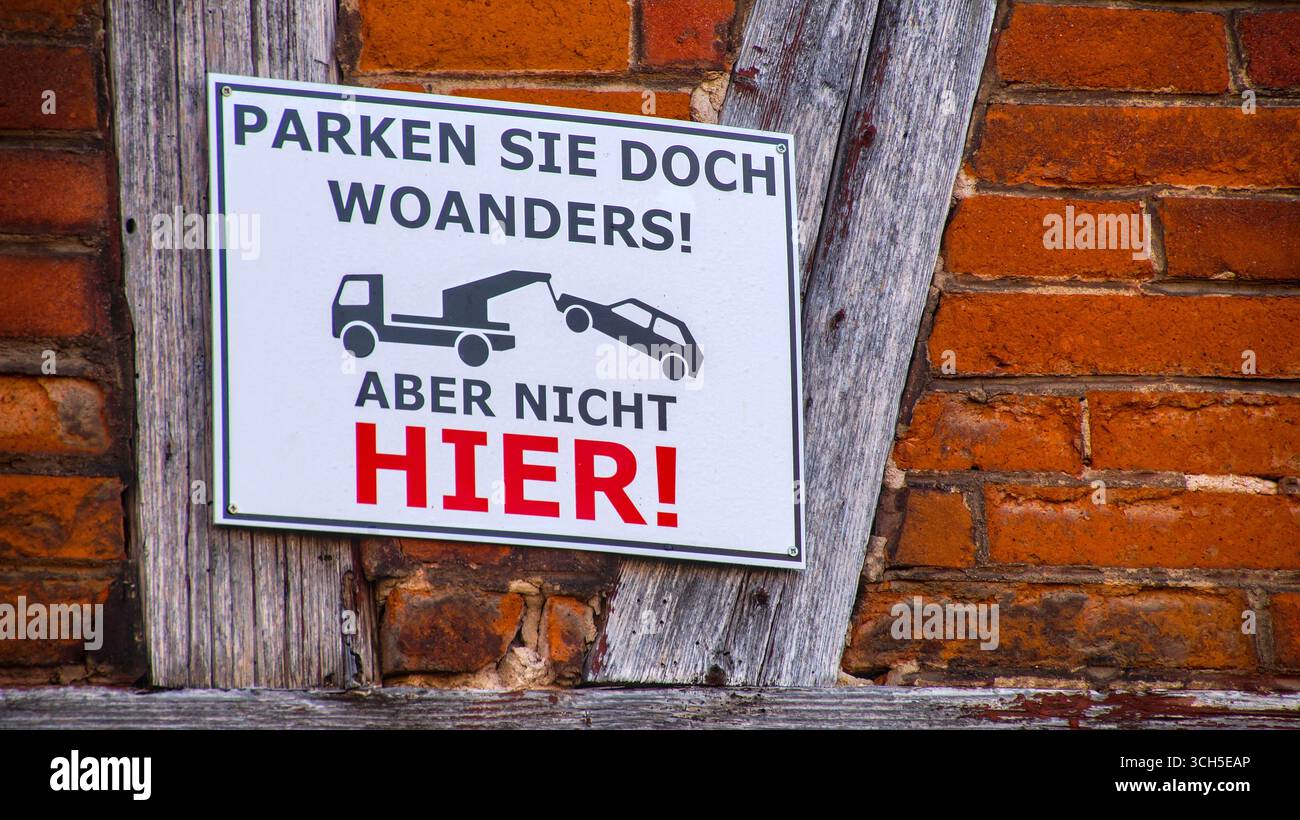 Signe humoristique de non-stationnement sur un mur de maison de briques avec le texte « Park where other, but not HERE ! » Banque D'Images