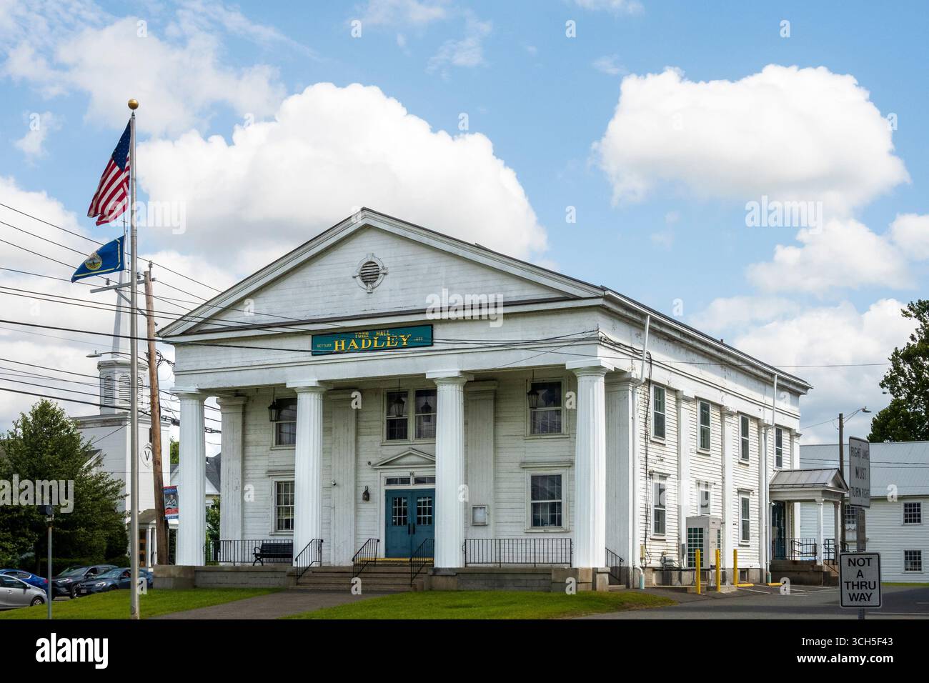 Hadley, ma - US - 24 août 2025 L'hôtel de ville de Hadley, un grand hôtel de ville blanc de style colonial avec des colonnes et des drapeaux proéminents, sous un SK partiellement nuageux Banque D'Images