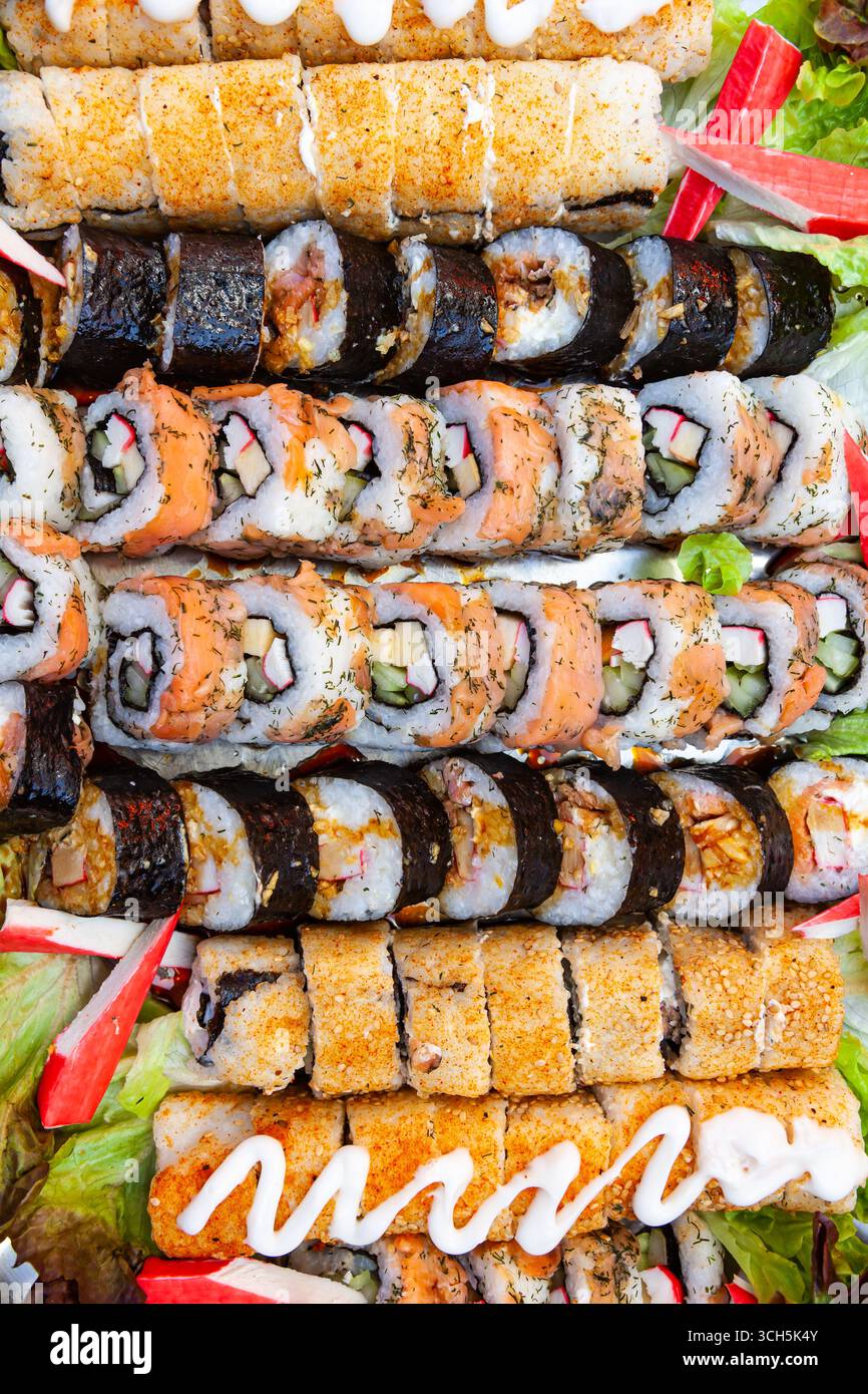 Une grande portion sur un plateau de petits pains cuits et de sushis de différents types, vue de dessus. Banque D'Images