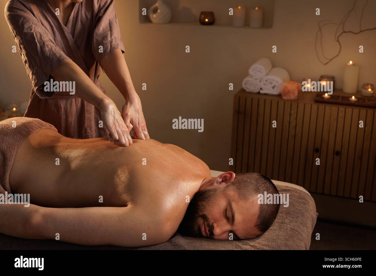 Thérapeute féminine expérimentée effectue un massage profond du dos des tissus pour un client masculin dans un spa paisible pour une relaxation ultime et un soulagement du stress Banque D'Images
