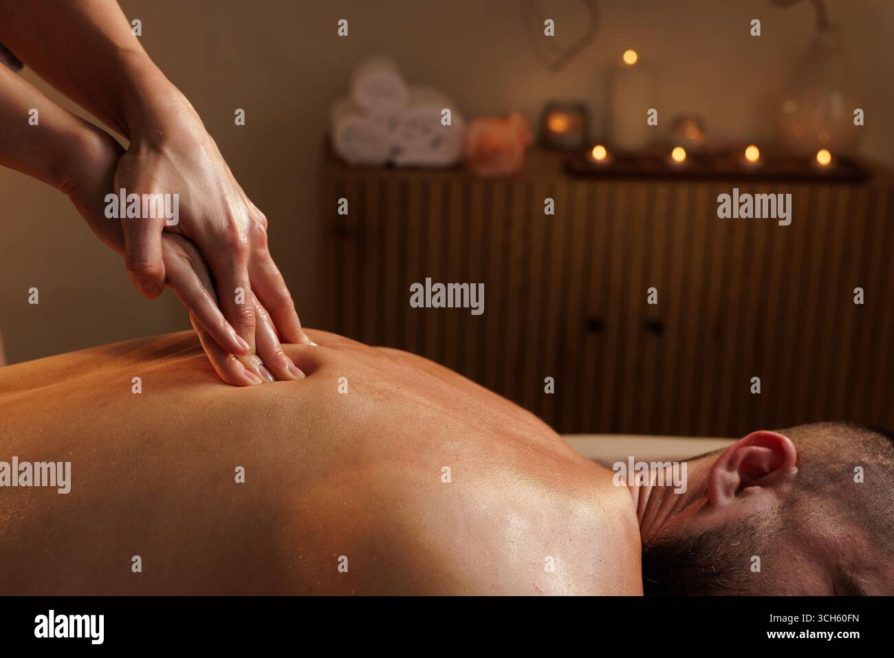 Thérapeute féminine professionnelle effectuant un massage du dos des tissus profonds pour un client masculin dans un cadre de spa paisible pour le soulagement du stress et le bien-être Banque D'Images