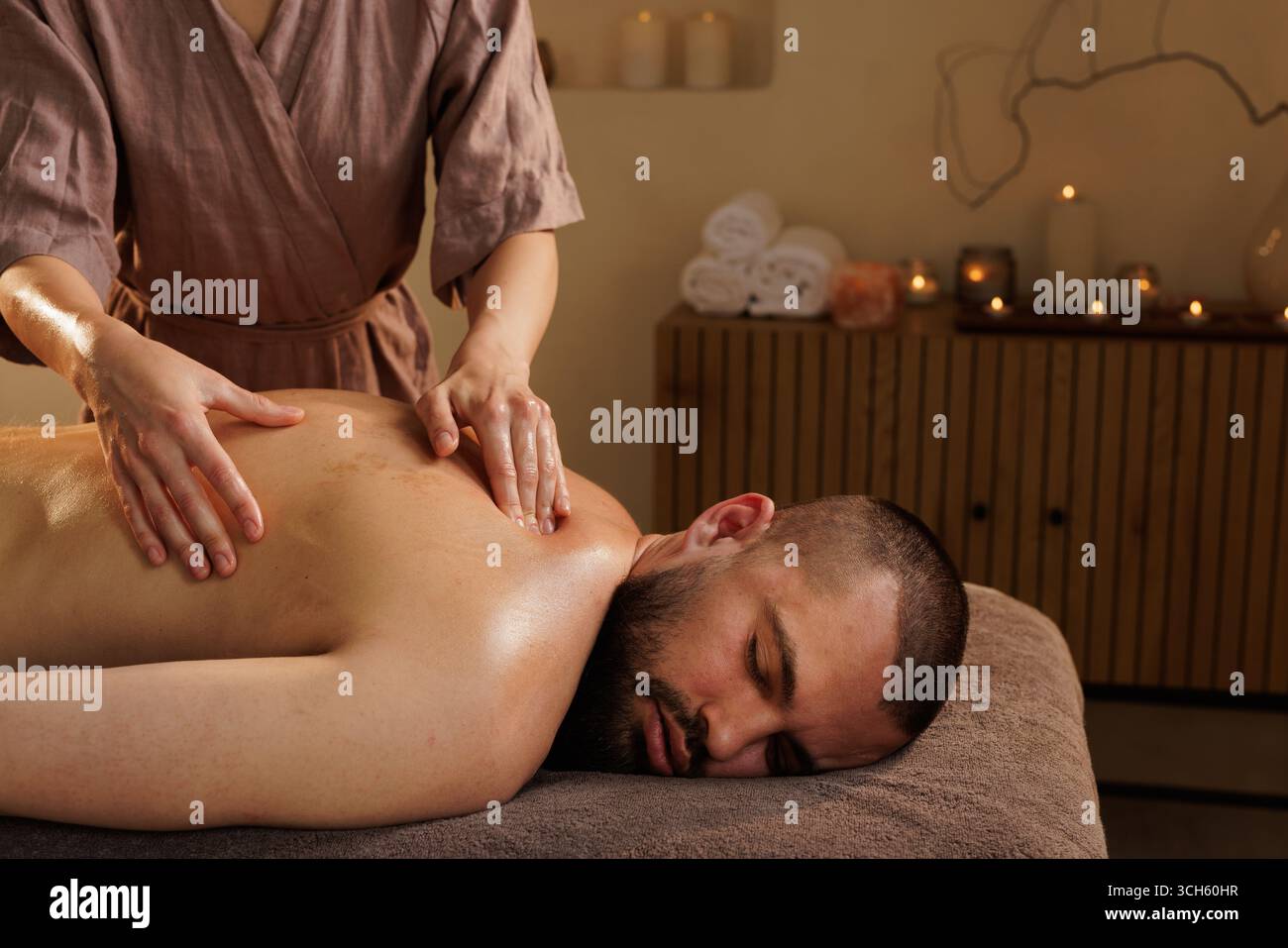 Thérapeute féminine professionnelle donnant un massage relaxant du dos à un client masculin dans un spa tranquille pour la santé et le bien-être Banque D'Images
