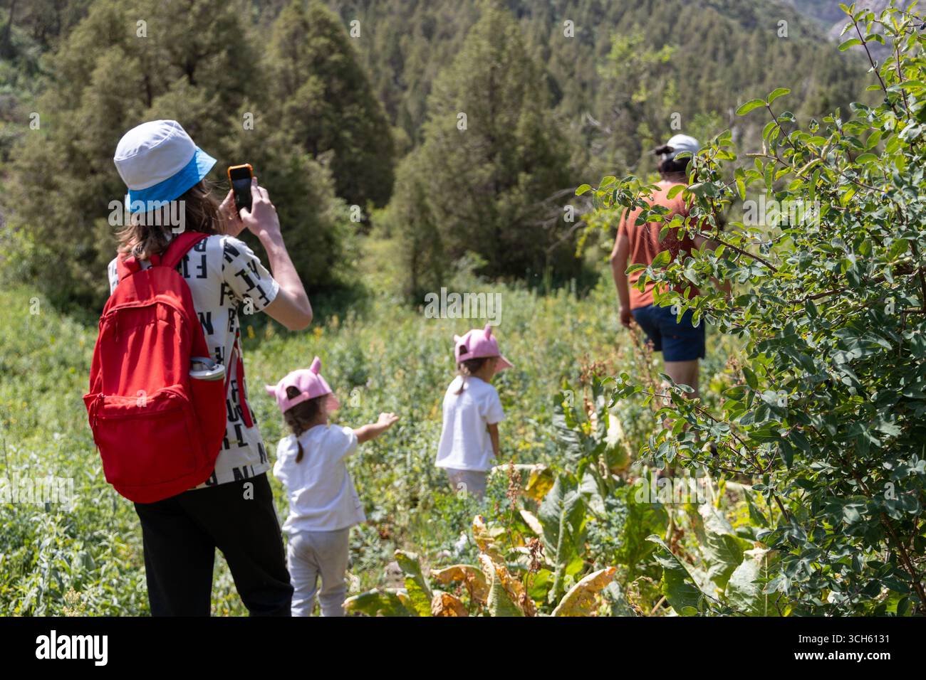 SHYMKENT, KAZAKHSTAN- 22 JUIN 2025 : père, fils et deux filles marchant ensemble sur un sentier de randonnée en montagne entouré par la nature. Vue arrière du Banque D'Images