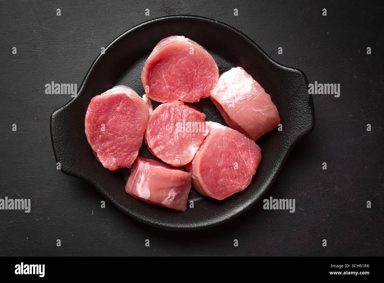 Médaillons de filet de porc non cuit prêts à cuire sur fond noir, vue de dessus. Morceaux de viande juteuse fraîche, concept de cuisine. Banque D'Images