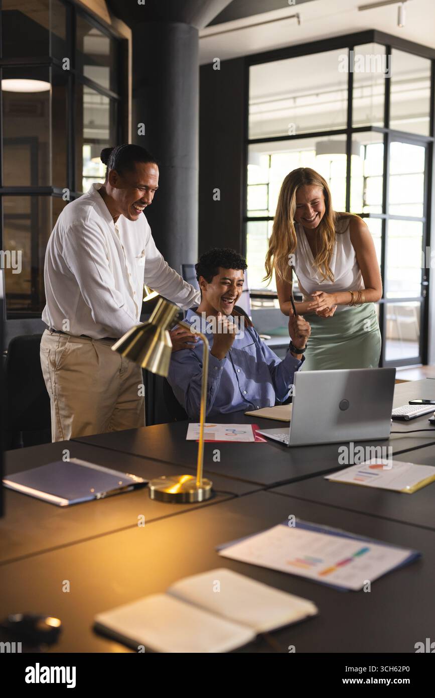 Équipe d'affaires célébrant le succès avec ordinateur portable dans un bureau moderne, se sentant excité Banque D'Images Équipe d'affaires célébrant le succès avec ordinateur portable dans un bureau moderne, se sentant excité Banque D'Images