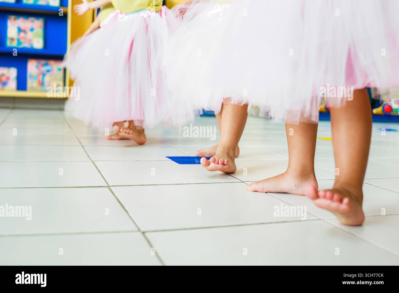 Enfants pieds nus dansant en classe portant un tutus rose - activité scolaire, concept d'éducation sportive Banque D'Images