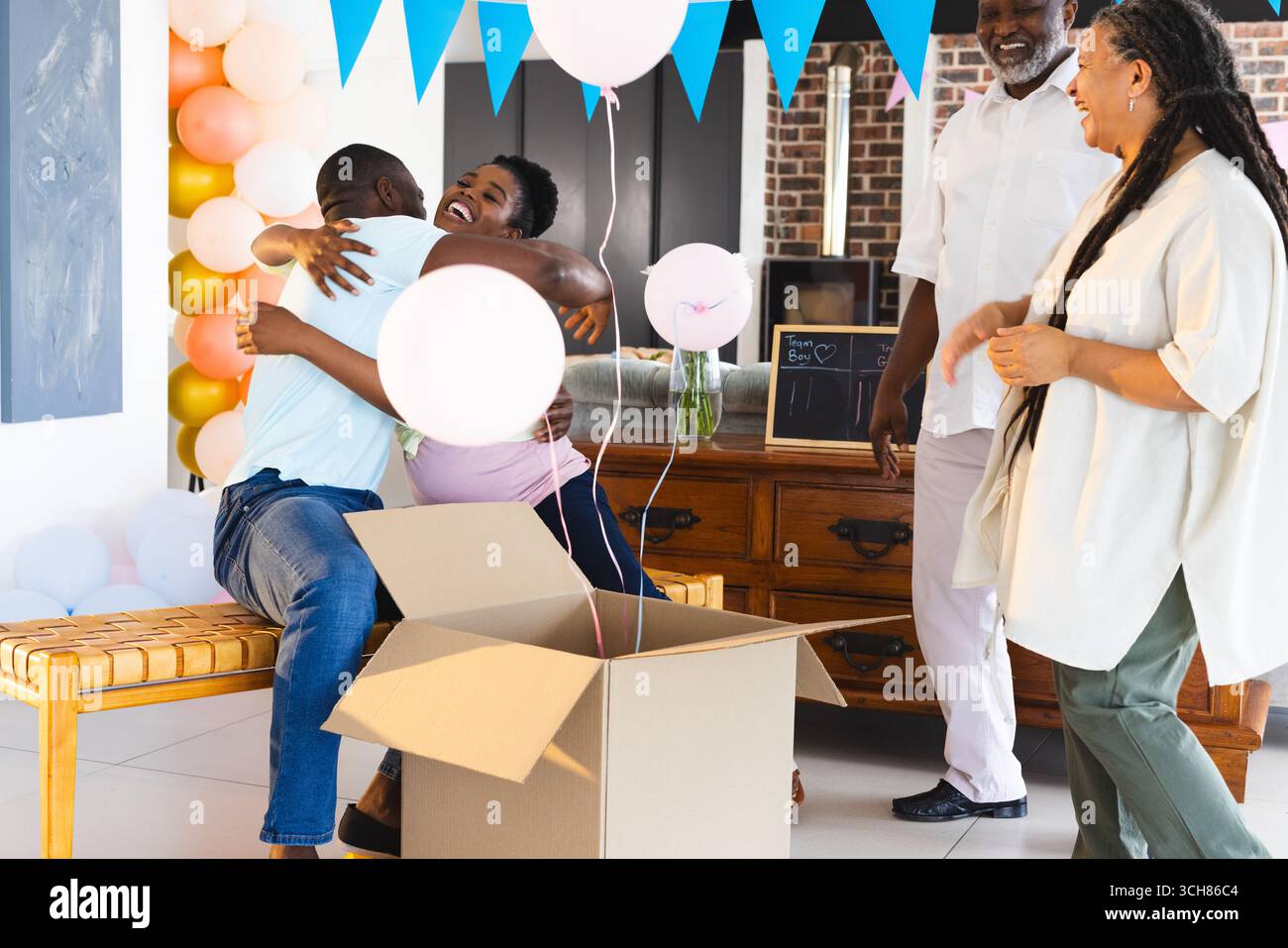 Gender Reveal, célébrant ensemble, la famille afro-américaine avec des ballons partageant des câlins joyeux et des s. Banque D'Images
