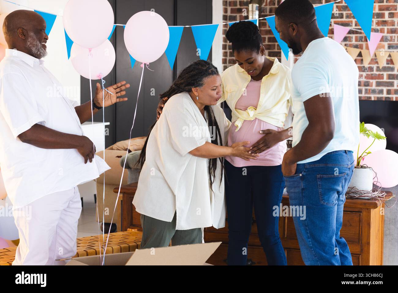 Gender Reveal, famille célébrant la douche de bébé, touchant le ventre de la femme enceinte, souriant et joyeux Banque D'Images