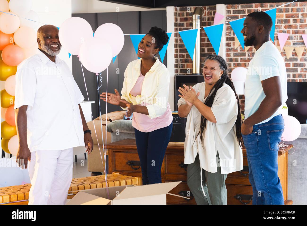 Révéler le genre, célébrer avec des ballons et des décorations, famille partageant un rire joyeux à la maison Banque D'Images