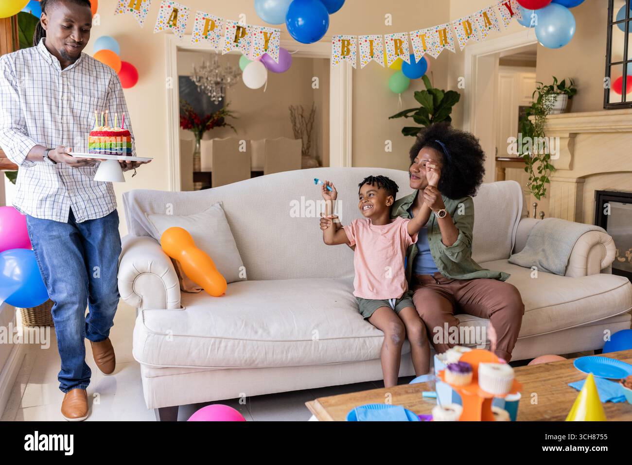 Père apportant un gâteau d'anniversaire pendant que mère et enfant célèbrent à la maison Banque D'Images