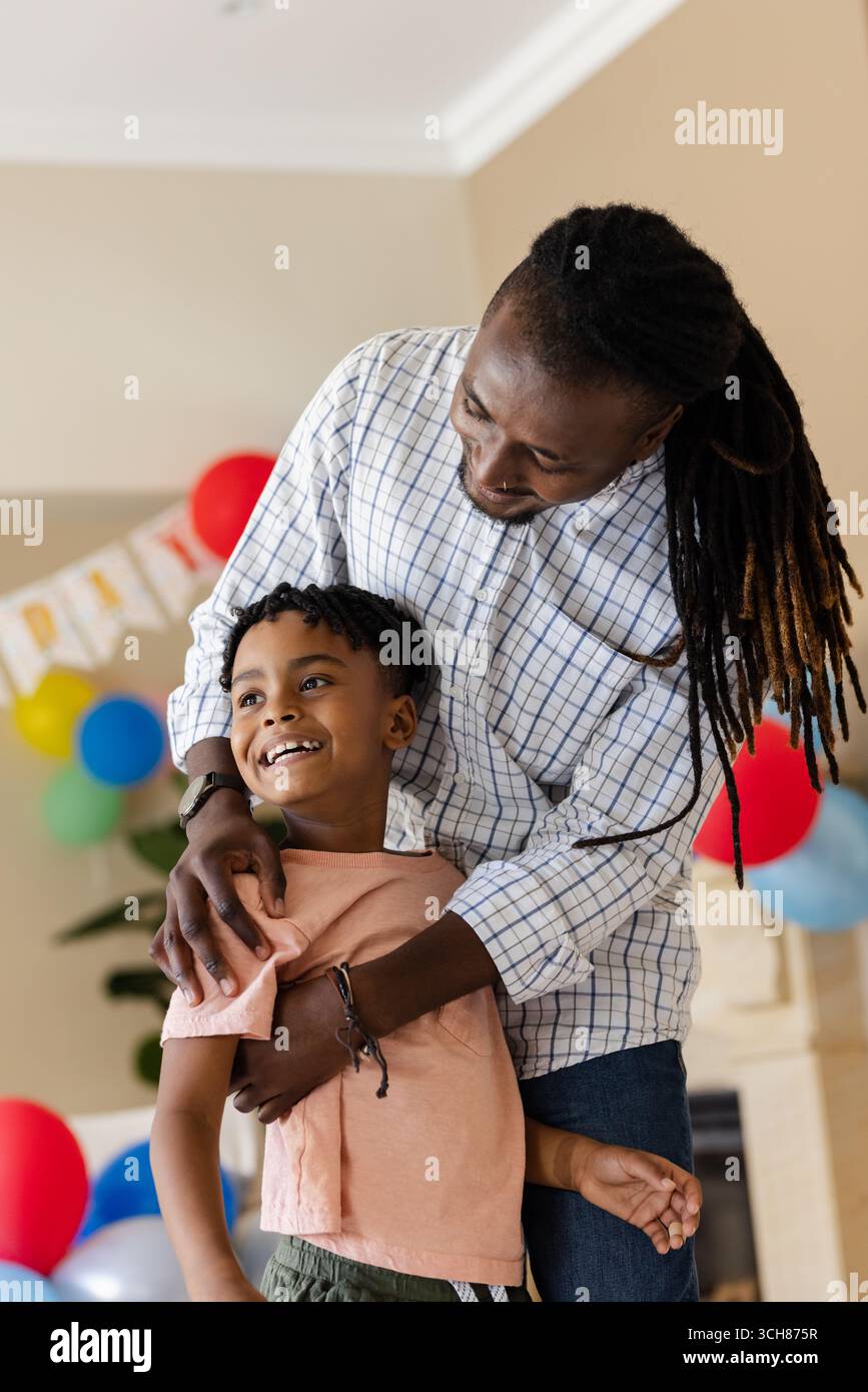 À la fête, père et fils riant ensemble à la maison pendant la célébration festive Banque D'Images À la fête, père et fils riant ensemble à la maison pendant la célébration festive Banque D'Images