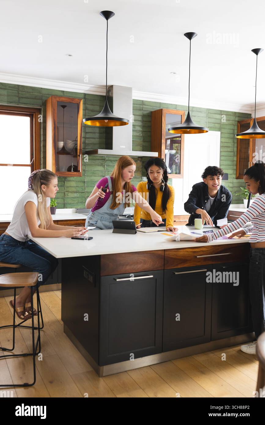 Collaboration sur le projet scolaire, amis adolescents utilisant la tablette et les notes dans la cuisine Banque D'Images